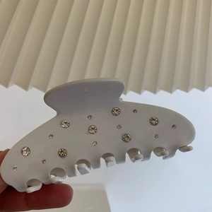 Pince à cheveux blanche en acétate avec strass scintillants et design de nœud élégant