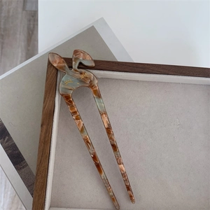 Dettaglio di un fermaglio per capelli a coniglio in acetato con elegante texture ambra e tartaruga