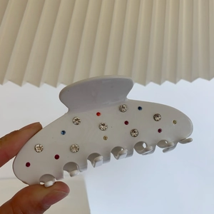 Détail d'une grande pince à cheveux crème ornée de strass multicolores et étincelants