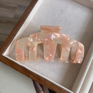 Vue détaillée d'une grande pince à cheveux marbrée en acétate aux tons rose doux et crème
