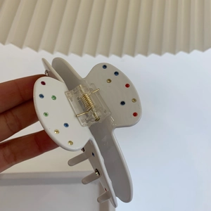 Détail de la pince à cheveux Y2K blanche avec strass colorés et ressort doré robuste