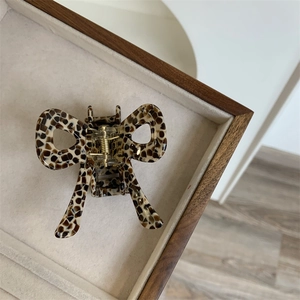 Macro view of leopard print bow hair claw made of acetate on a beige velvet tray