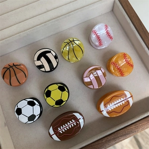 Vista superior de mini pinzas para el cabello con pelotas de deporte en bandeja beige