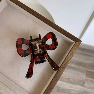 Macro detail of red and black plaid bow hair claw clip with golden metal spring
