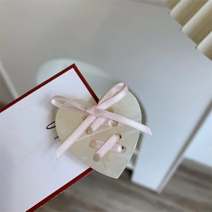 Détail d'un bouton en résine en forme de cœur avec un ruban de satin rose délicat