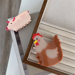 Detailed view of pink pig and brown hen hair claws on a wooden tray and book