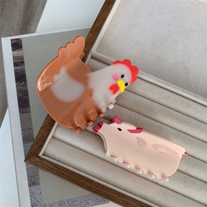 Cute animal hair claws with chicken and pink pig designs on a velvet jewelry tray