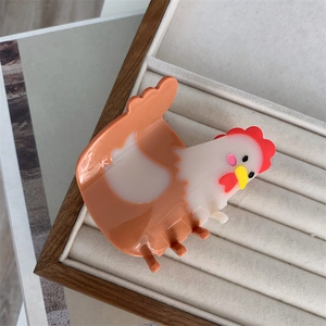Detailed macro shot of a cute hen-shaped hair claw clip in a grey jewelry organizer box