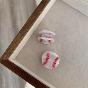 Primer plano de pinzas para el cabello de béisbol con costuras rojas en blanco perla