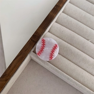 Detalle de pinza para el pelo redonda de béisbol con costuras rojas y textura de mármol suave