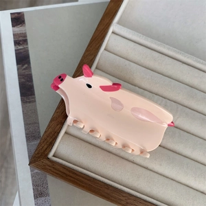 Close-up of a cute pink pig hair claw clip with glossy finish in a velvet display box