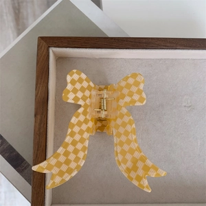 Detail view of yellow checkered ribbon hair claw clip on a felt display tray