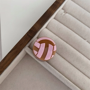 Primer plano de pinza de pelo de resina rosa y marrón con logo geométrico de doble T