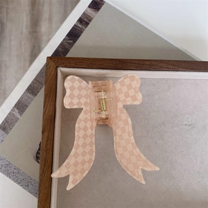 Detail of pink checkerboard bow hair claw clip with golden metal spring mechanism