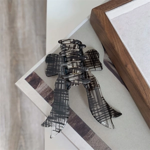 Detail of a plaid bow hair claw clip made of translucent resin on a lifestyle background