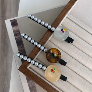 Three-piece set of elegant faux pearl hair clips with colorful rhinestone accents in a box