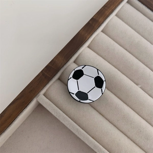 Detalle de una pinza para el cabello con forma de balón de fútbol sobre bandeja de joyas