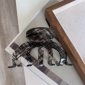 Close-up of translucent acrylic hair claw clip with unique black textured pattern design