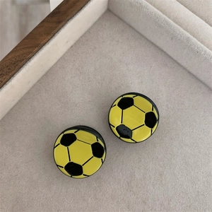 Detalle de pendientes de fútbol en esmalte amarillo y negro sobre bandeja de terciopelo