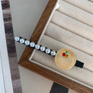 Detail of a metal hair clip with white pearls and a crystal-embedded resin button