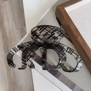 Detail shot of a large translucent grey hair claw clip with black grid texture patterns