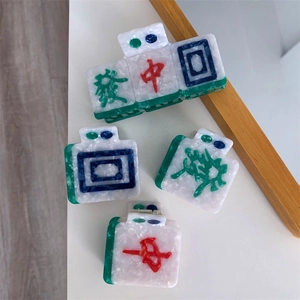 Detail of mahjong-themed hair claws featuring Chinese characters on marble acetate material