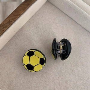 Detalle de mini pinzas para el cabello con forma de balón de fútbol en amarillo y negro