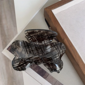 Detailed view of the black cross-textured butterfly hair claw clip on wooden background
