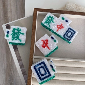 Detail view of Mahjong-inspired acetate hair claws with 3D engraved characters on a tray
