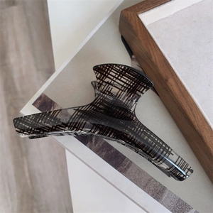 Close-up of translucent dark grey acrylic hair claw clip with black checkered texture