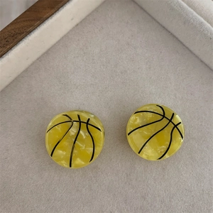Detalle de pendientes de resina amarillos creativos con forma de balón de baloncesto