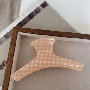 Détail de la grande pince à cheveux à damier crème sur un plateau en lin doux