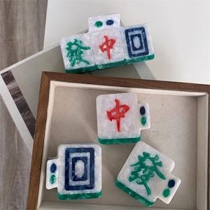 Detailed view of creative Mahjong acetate hair claws in green and white marble texture