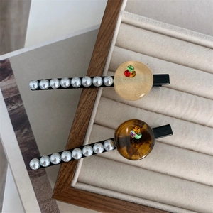 Close-up of vintage pearl hair clips with colorful rhinestones in a velvet jewelry box