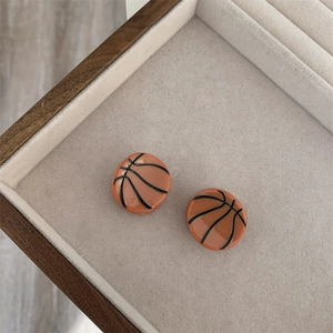 Primer plano detallado de pendientes de baloncesto en una bandeja de joyería de beige