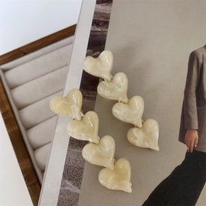 Cream marble heart hair clips with golden metal base on stylish background
