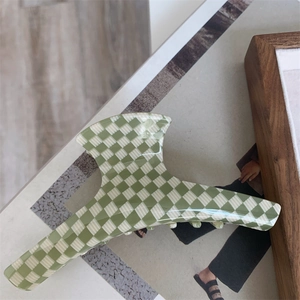 Détail d'une pince à cheveux à damier vert et beige sur un fond de magazine d'art