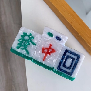 Macro shot of Mahjong hair claw clip with 發 and 中 symbols in marble acetate texture