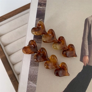 Detail shot of two amber resin heart hair clips with a smooth tortoise shell texture