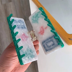 Detail of acetate shark clip featuring Chinese mahjong patterns and green translucent teeth