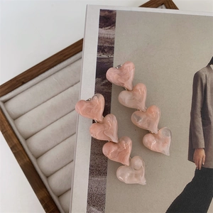 Detail of sweet pink marble acetate heart hair clips on a soft beige jewelry display
