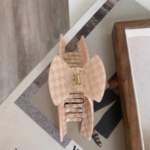 Détail d'une grande pince à cheveux en acrylique avec motif à damier beige