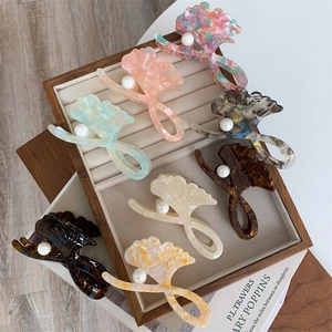 Close-up of marble acetate hair claws with ginkgo leaf design and pearl details