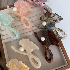 Elegant ginkgo leaf hair claws with pearls in colorful acetate finishes on wood