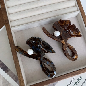 Close-up of ginkgo leaf hair claw with white pearl and amber tortoiseshell finish