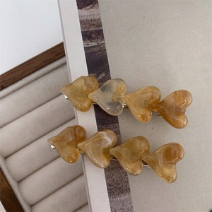 Detailed macro shot of amber marble acetate heart hair clips with silver metal base