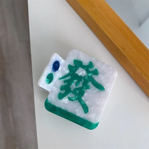 Macro shot of Mahjong hair claw clip featuring green luck character and marble texture