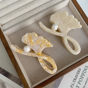 Detailed view of acetic acid ginkgo leaf hair claws with pearls in a jewelry display box