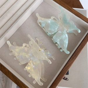 Détail de deux pinces à cheveux papillon vintage en blanc perlé et bleu clair sur un plateau