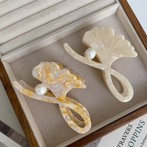 Detail of ginkgo leaf hair claws with pearl accents in acetate on a velvet tray